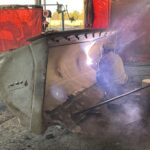man welding a bucket on the right side